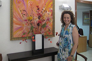 Dr. Maria del Carmen Caballero stands in front of an abstract painting.