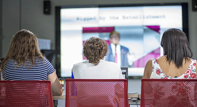 Students sitting in front of a media screen