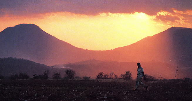Nicaraguan man walking with sun setting behind mountains in the background