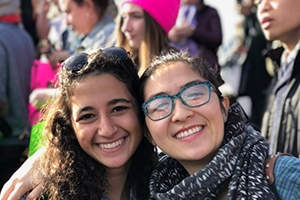 Christine Miyashiro (right) and fellow AU student Maia Banayan at the 2018 Women’s March, standing in front of crowd.