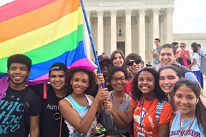 Students hold a rainbow pride flag in front of the Supreme Court.