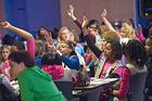 Girl Scouts raise their hands for questions at a financial literacy seminar.