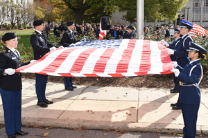 Men and women in military uniform holding the American flag.