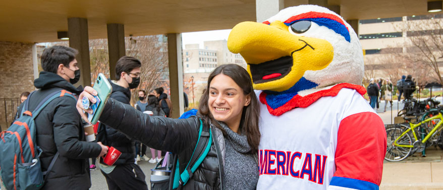 Student poses with AU Mascot Clawed Z Eagle