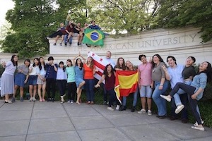 Abroad at AU students holding signs at main university gate.