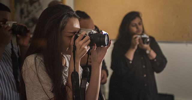 Several students hold cameras
