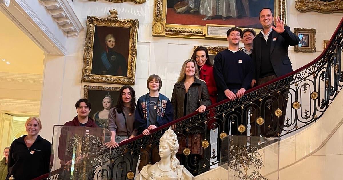 Students on the Hillwood House stairs with paintings of Russian royalty.