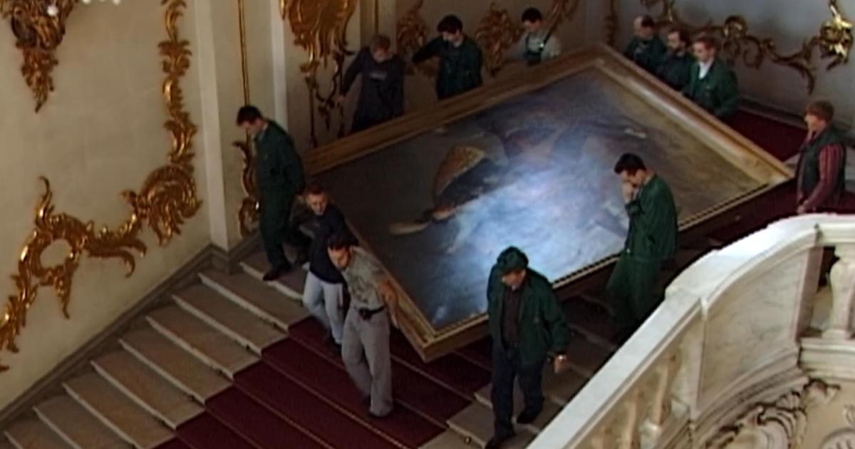 Hermitage Dwellers film still of workers carrying a large portrait down stairs.