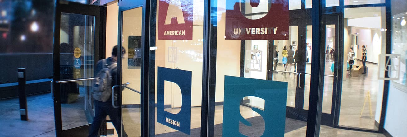 Students walking through Katzen door with "AU Design Show" graphics on glass
