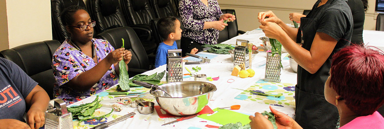 Adults and children sit at a table and handle food