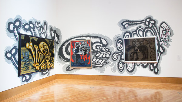 Three of Luna's paintings as installed overtop images of skeletons and bones applied directly to the gallery wall