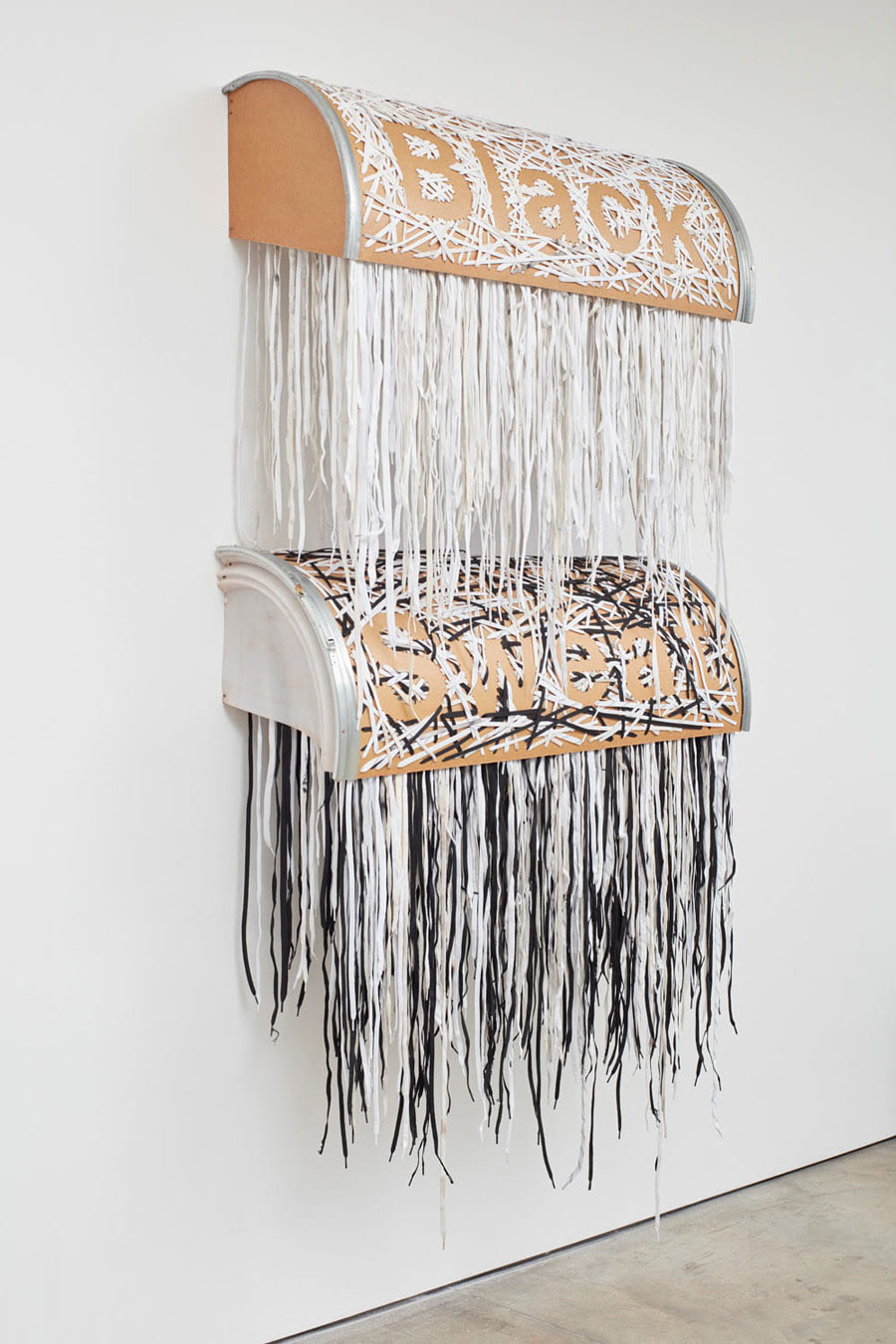 Nari Ward, Black Sweat, 2019. Shoelaces, shipping barrel. Shoelaces stitched into stacked halves of shipping barrel. The negative space between the shoelaces reads, "Black Sweat"