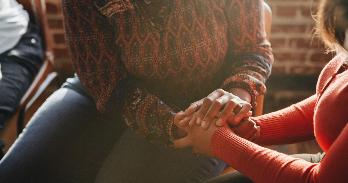 Two people of color holding hands compassionately