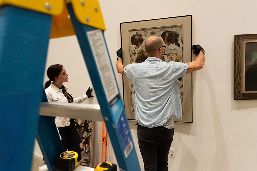 People hang art on the wall of the AU Museum