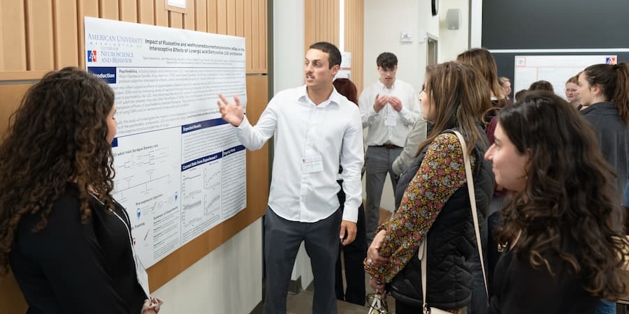 Student presents poster to audience at Mathias Conference