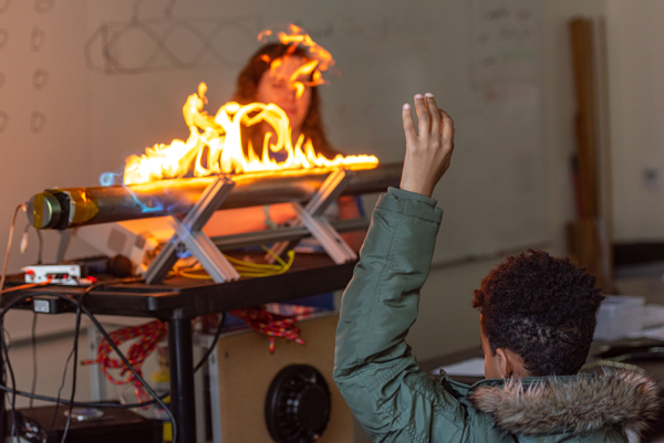 A visiting middle school student observes a demonstration on the effect of sound waves.