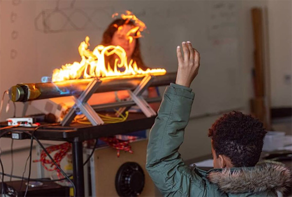 A visiting student observes a demonstration on the effect of sound waves.