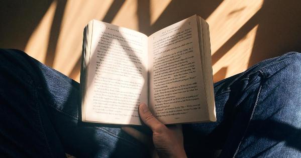 A person holding a book and sitting with crossed legs on the floor. Credit Blaz Photo