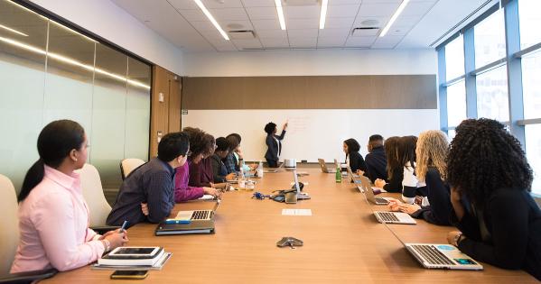 A Black woman gives a presentation to a conference room audience of women of color. Photo by WOC in Tech Chat.