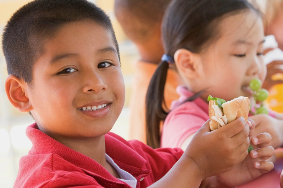 Children eating sandwiches and apples for lunch