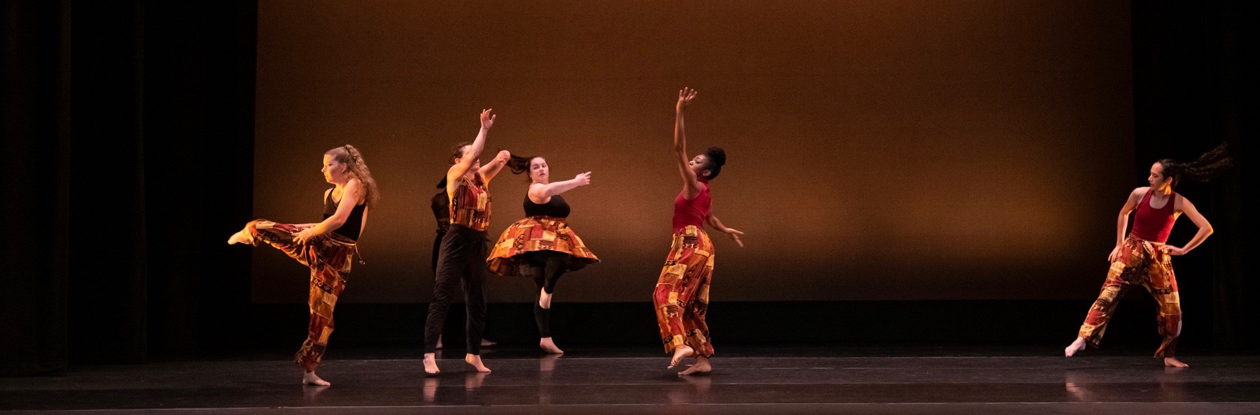 Dancers perform with glowing sunset of light behind them at the Greenberg Theatre