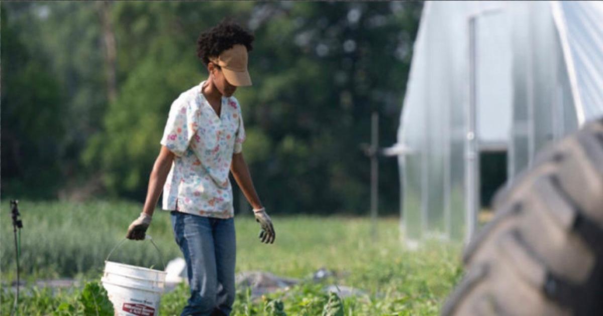Farmer holding a bucket in a field, taken by Scott Streble