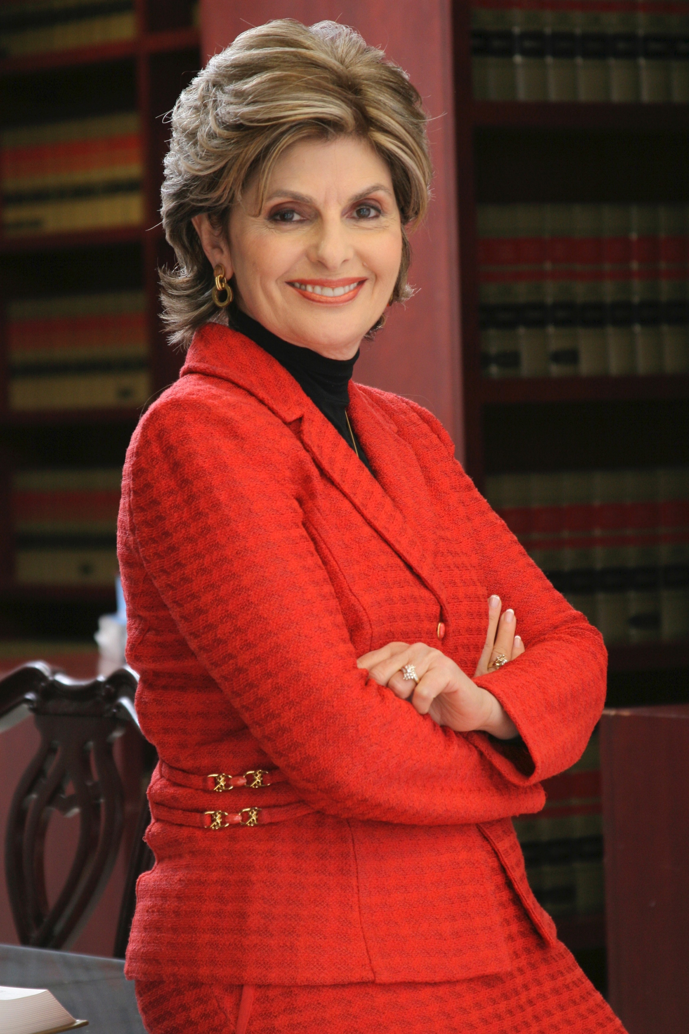 woman with short blonde hair in a red skirt suit smiles at the camera