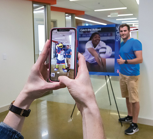 AR-poster-clawed A prospective student poses with an augmented reality Clawed mascot