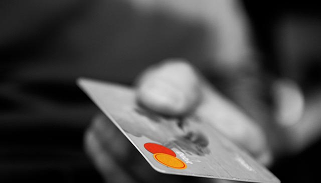 Credit card with the word "Debit," visible, held in someone's hand