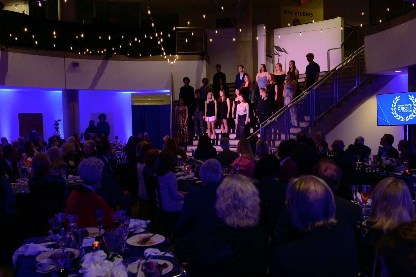 Students sing together on the steps in the Katzen rotunda.