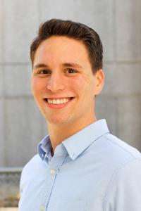 AU Student, Aaron, wearing a light blue collared shirt and smiling