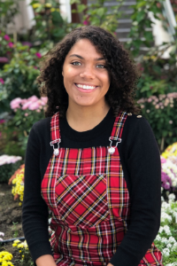 AU Student, Hannah, wearing plaid overalls with a black shirt, smiling at the camera