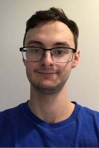 AU Student, Isaac, standing smiling with a blue sports top on