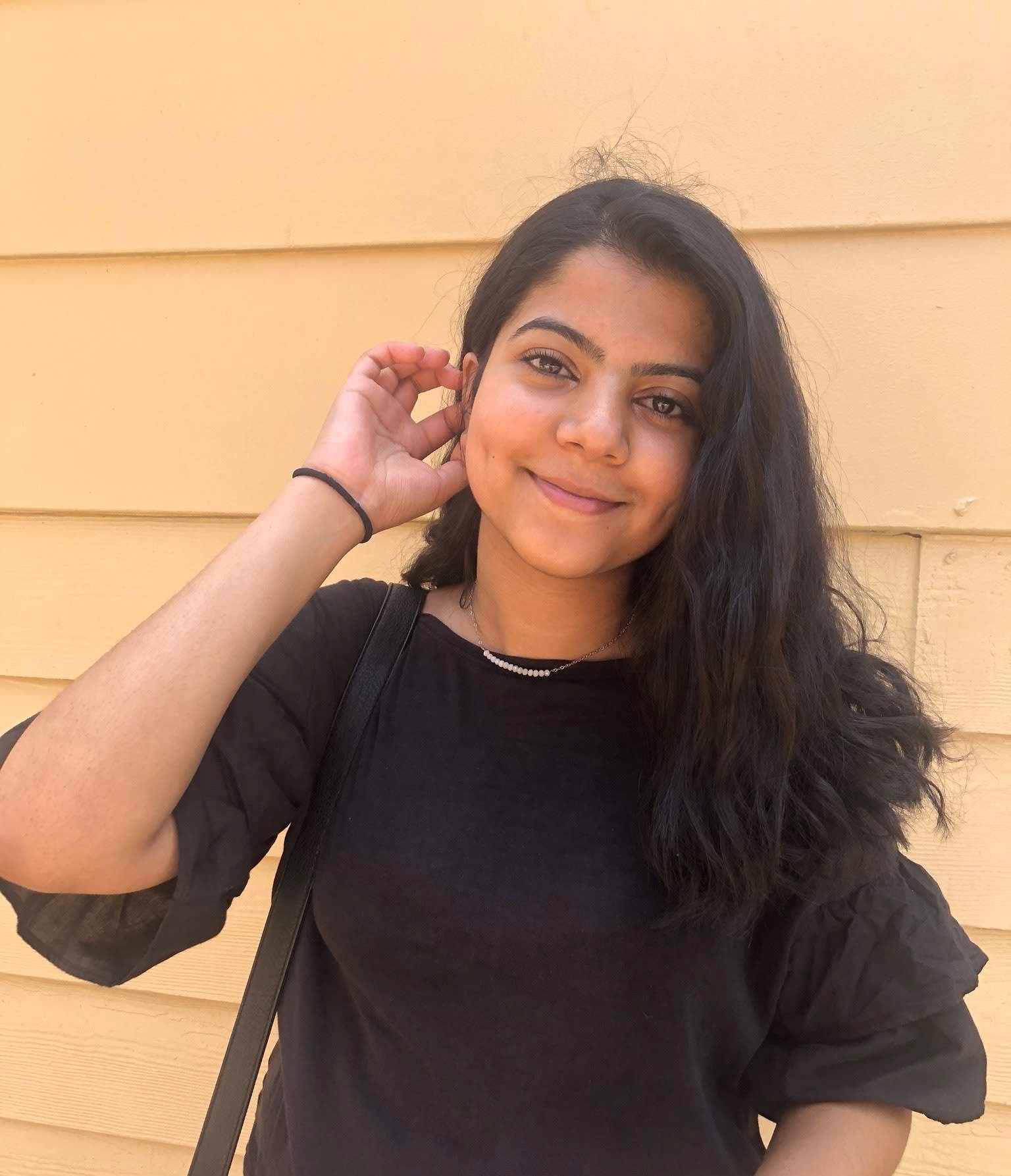 AU Student, Momal Rizvi, wearing a black blouse and smiling