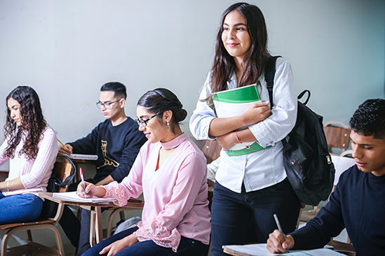 Student standing in classroom holding books