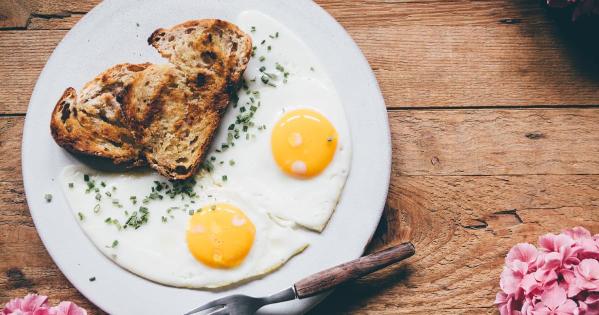 Plate of sunny side up eggs and a piece of toast on a wooden table