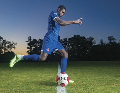 David Coly kicks a soccer ball at dusk at Reeves Field