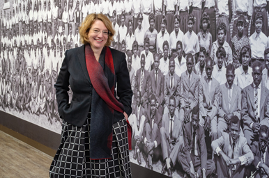 Laura Brower Hagood stands in front of a panoramic photo of randall junior high class of 1954 at the dc history center