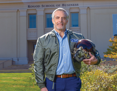 Joseph Mortati stands in front of the Kogod School of Business in Air Force flight jacket