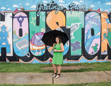 Avital Ingber in front of a mural that reads 