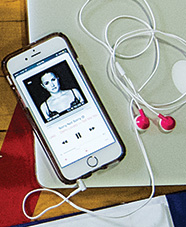 iPhone with music app open and pink headphones connected