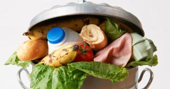 Food spills out of a trash can. Photo from Getty.