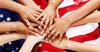 hands stacked on top of each other over American flag