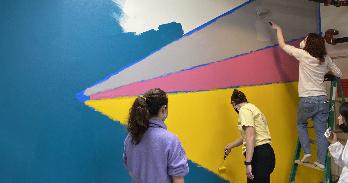 AU students paint a wall at the Latin American Youth Center Career Academy in DC for the Black History Month Day of Service.