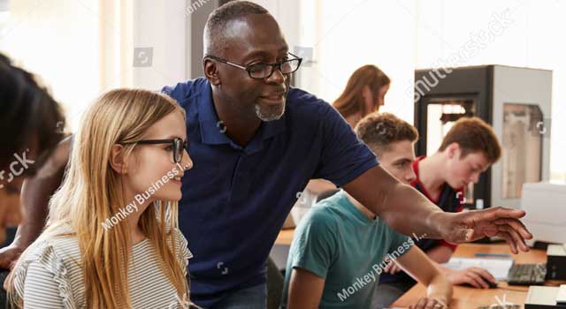 Teacher going over points with student on a desktop