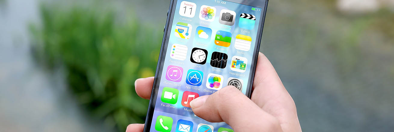 person holding iPhone with screen full of various apps