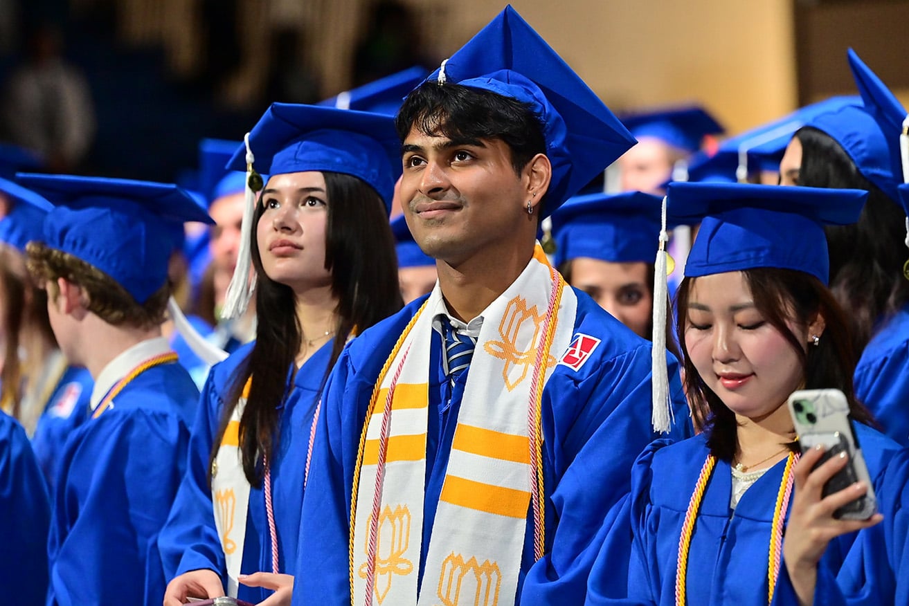 SIS students in regalia smiling at commencement.
