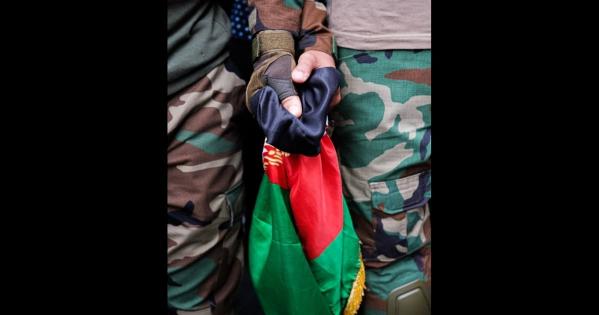 Two hands hold an Afghan flag.