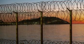 Ceuta, Spanish city in North Africa, seen from Morocco behind a thorn wire fence located on the Moroccan border against a stunning sunset over the sea.