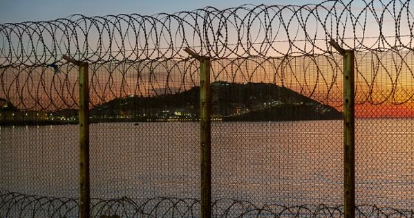Ceuta, Spanish city in North Africa, seen from Morocco behind a thorn wire fence located on the Moroccan border against a stunning sunset over the sea.